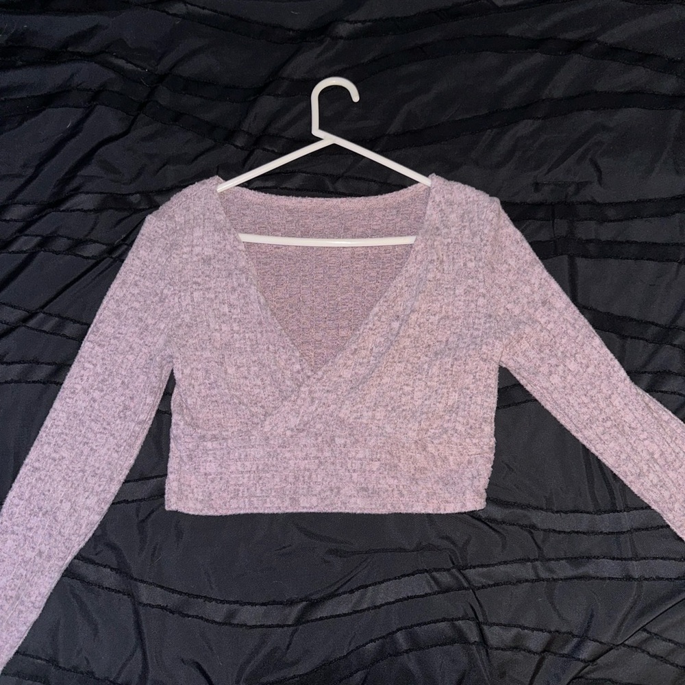 It is a purple V-neck crop top with long sleeves
